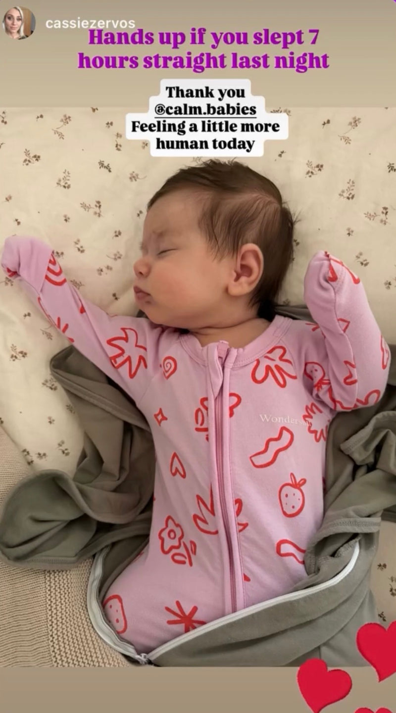 Baby in a pink onesie with red designs lying on a textured surface, with text overlay.